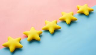 5 gold stars on a half pale blue half pale pink background slanted upwards