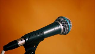 Orange background with a microphone in the foreground.