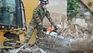 Man in camo cutting wood with a chainsaw